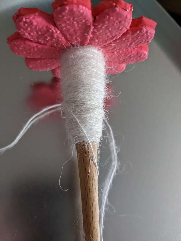 A spindle with a pink flower whorl. The nettle singles are on the spindle. It has a fluffy halo.